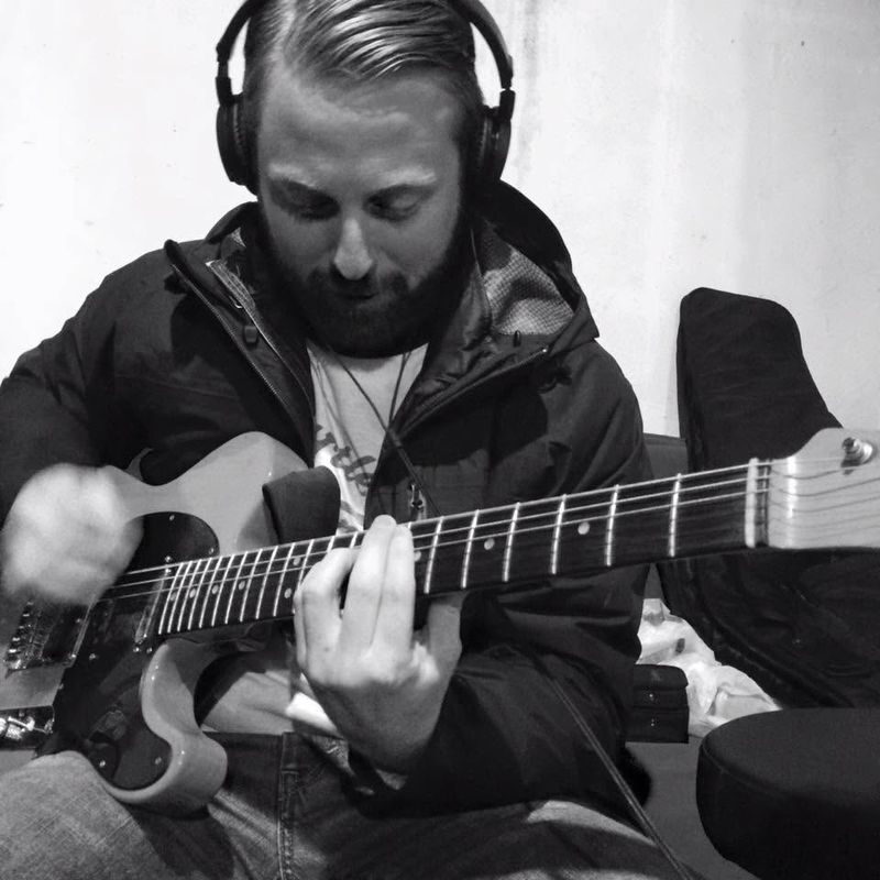 A band member in headphones playing electric guitar