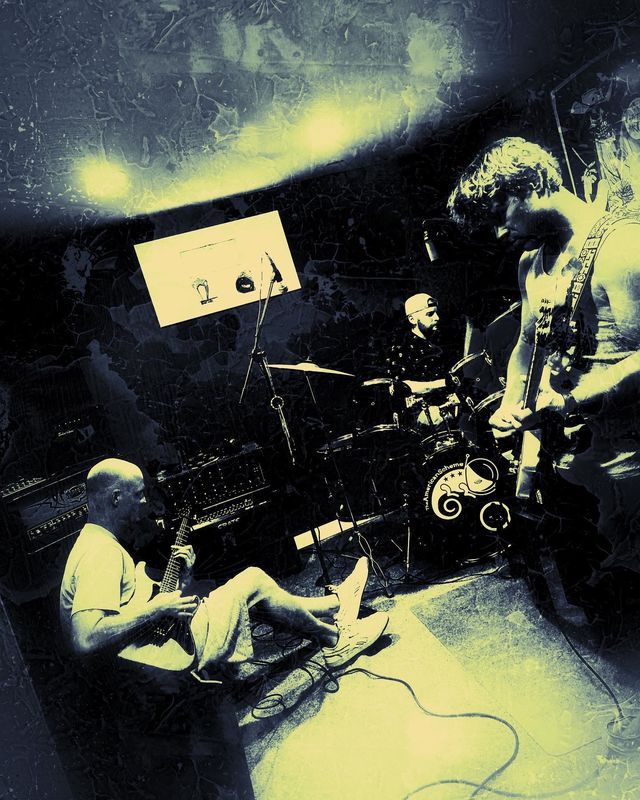 The band playing live in the practice room, yellow and navy duotone